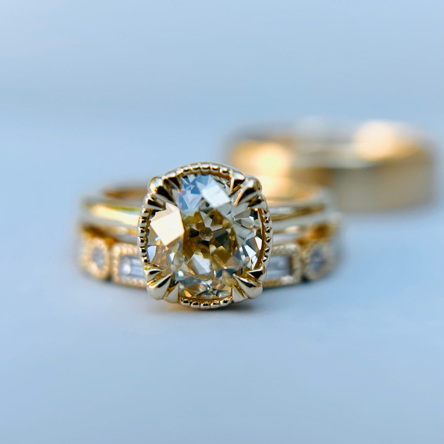 Elegant engagement ring with a large oval diamond set in a gold band. Surrounding bands offer intricate detailing, exuding luxury and sophistication.