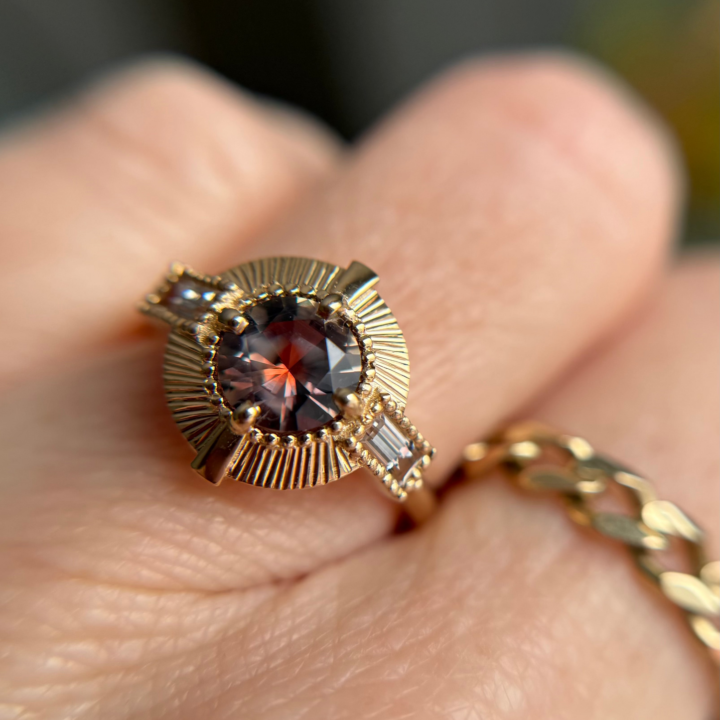 Gold ring with a pink almost red montana sapphhire gemstone on a person's finger
